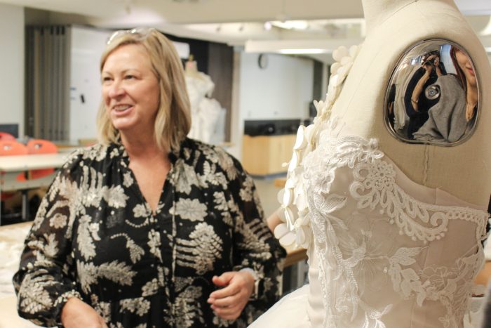 Kelly Midgley in front of a wedding dress designed by Otis students during upcycling mentorship project
