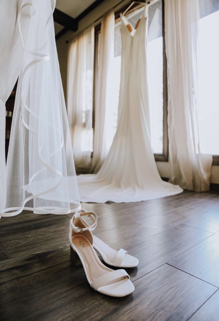 Fernanda wedding dress by Maggie Sottero hanging behind veil and wedding heels