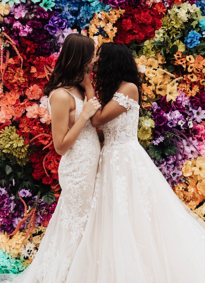 Colorful floral backdrop for LGBTQ+ wedding ideas with bride wearing Harlem by Maggie Sottero