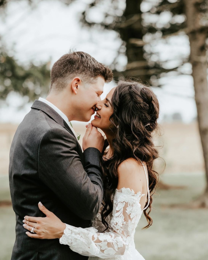 Bride wearing Stevie long sleeve wedding dress by Maggie Sottero kissing her husband