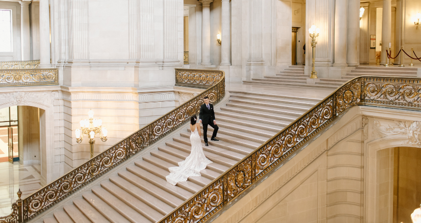 Bride wearing minimony courthouse wedding dress walking up the stairs to her husband