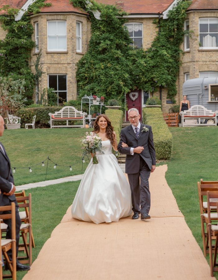 Bride wearing Selena by Maggie Sottero walking down the aisle with her father