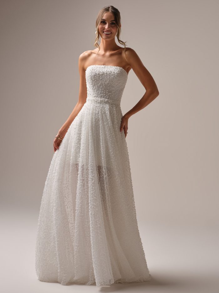 Strapless beaded wedding dress with a detachable overskirt, featuring textured pearl-like embellishments and a modern A-line silhouette.