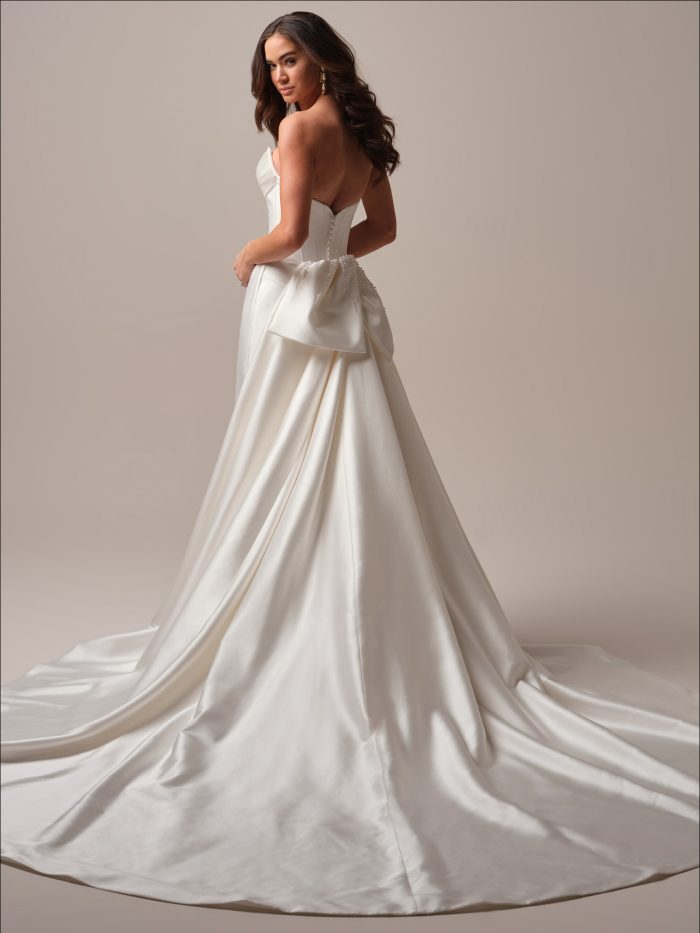 Bride wearing a glamorous bow detachable bridal train with her simple fit and flare wedding gown