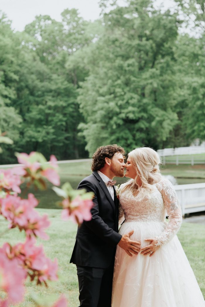 Brittany wearing one of Maggie Sottero's maternity wedding dresses and her husband touching her baby bump