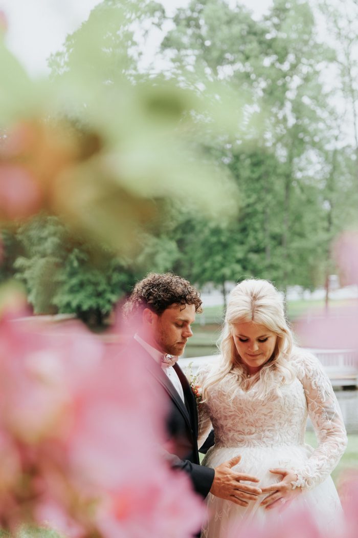 Brittany wearing one of Maggie Sottero's maternity wedding dresses and her husband touching her baby bump