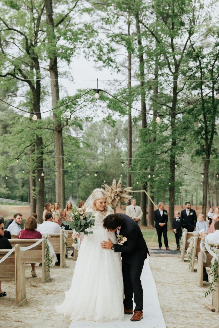 Brittany wearing one of Maggie Sottero's maternity wedding dresses and her husband touching her baby bump