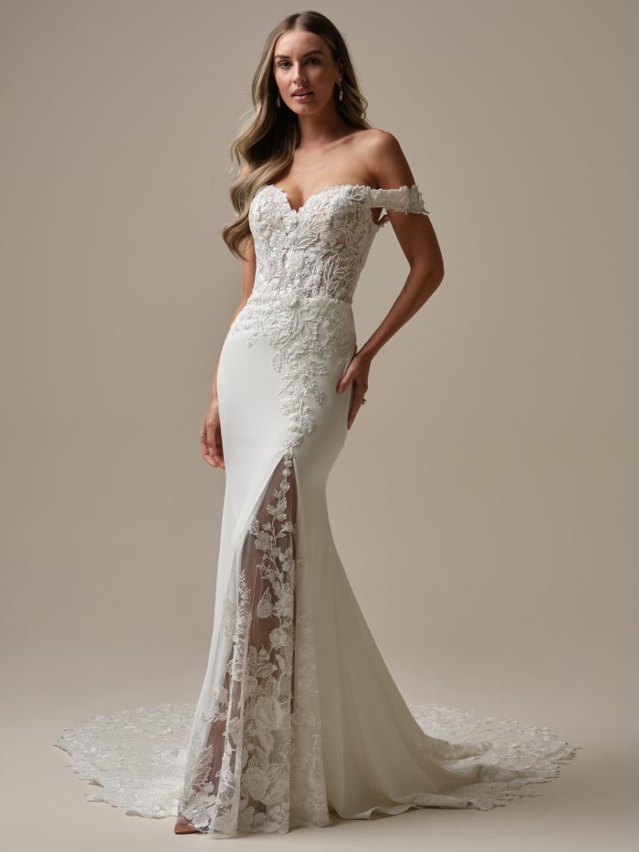 Bride wearing the Adeline fit-and-flare wedding dress featuring a sheer lace bodice with beaded motifs, off-the-shoulder sleeves, and a lace illusion slit that adds a romantic, modern touch.