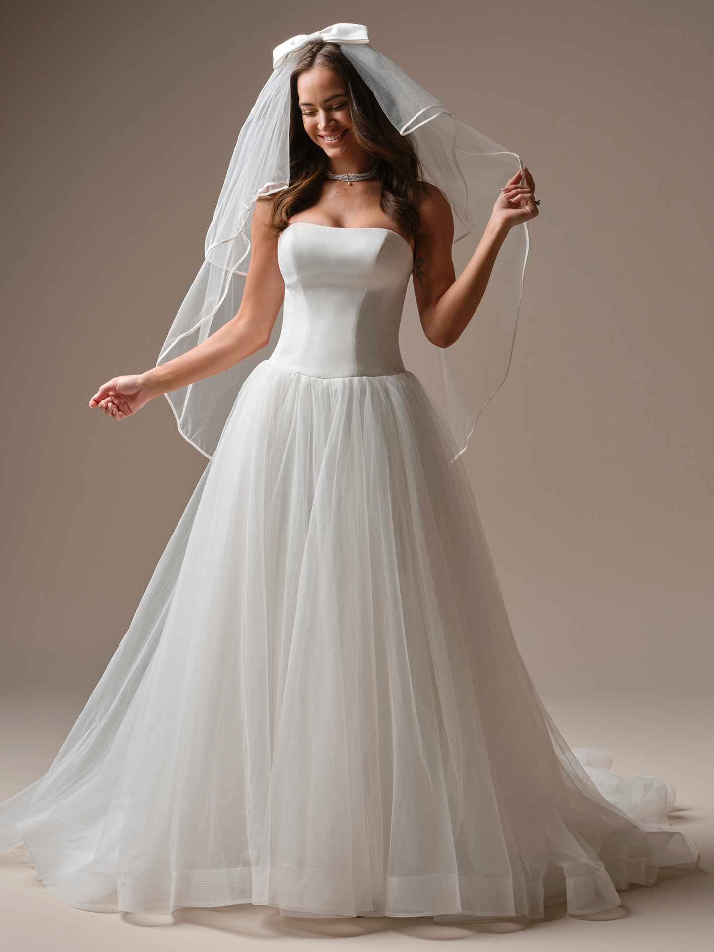 Fingertip-length veil in soft tulle with a delicate ribbon-trim edge, offering a clean, modern finish and lightweight movement.