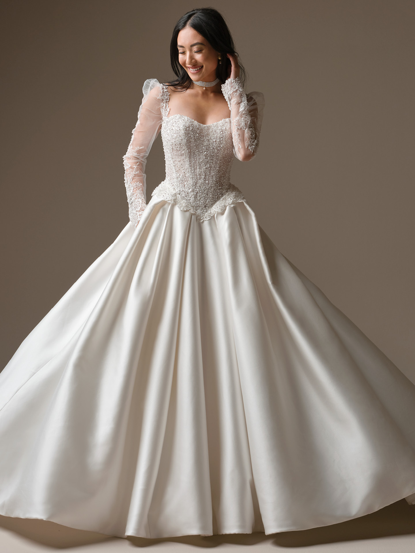 Beaded corset ballgown featuring sheer, detachable long sleeves that add coverage and drama to the bridal look.