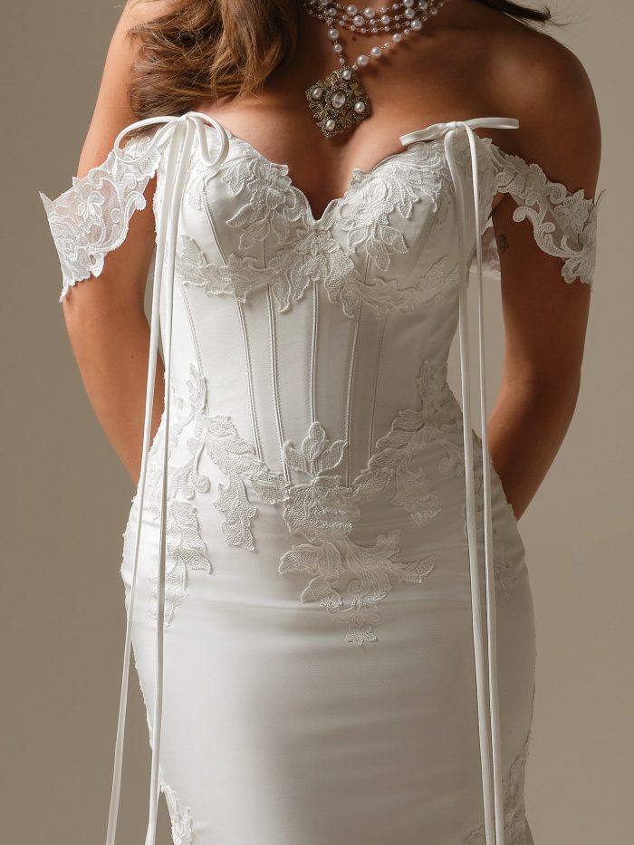 Strapless lace corset wedding dress styled with detachable off-the-shoulder lace sleeves finished with delicate ribbon ties for a soft, romantic detail.