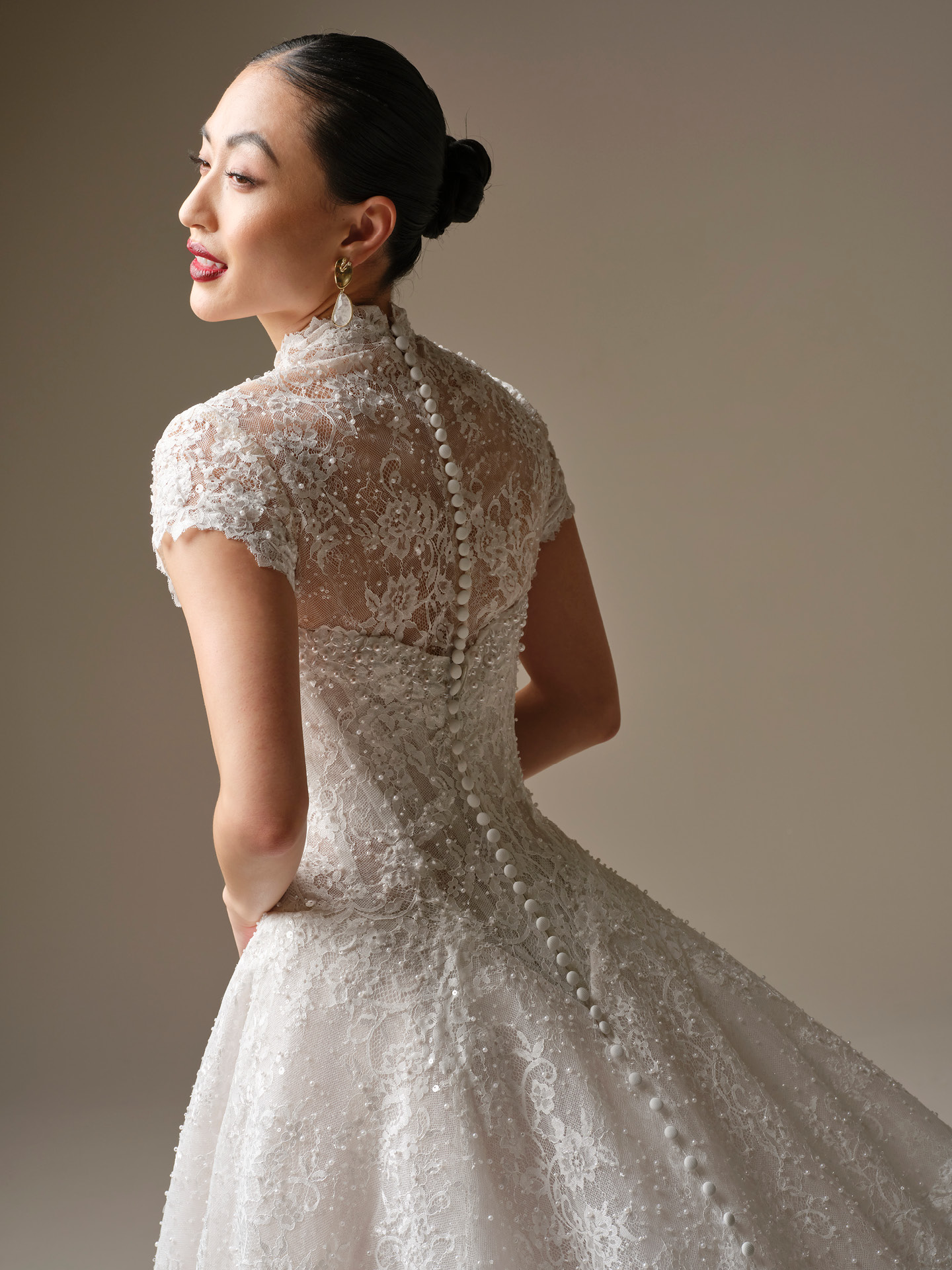 Sheer lace bridal jacket with cap sleeves and a high neckline, finished with covered buttons down the back for an elegant, vintage-inspired touch.