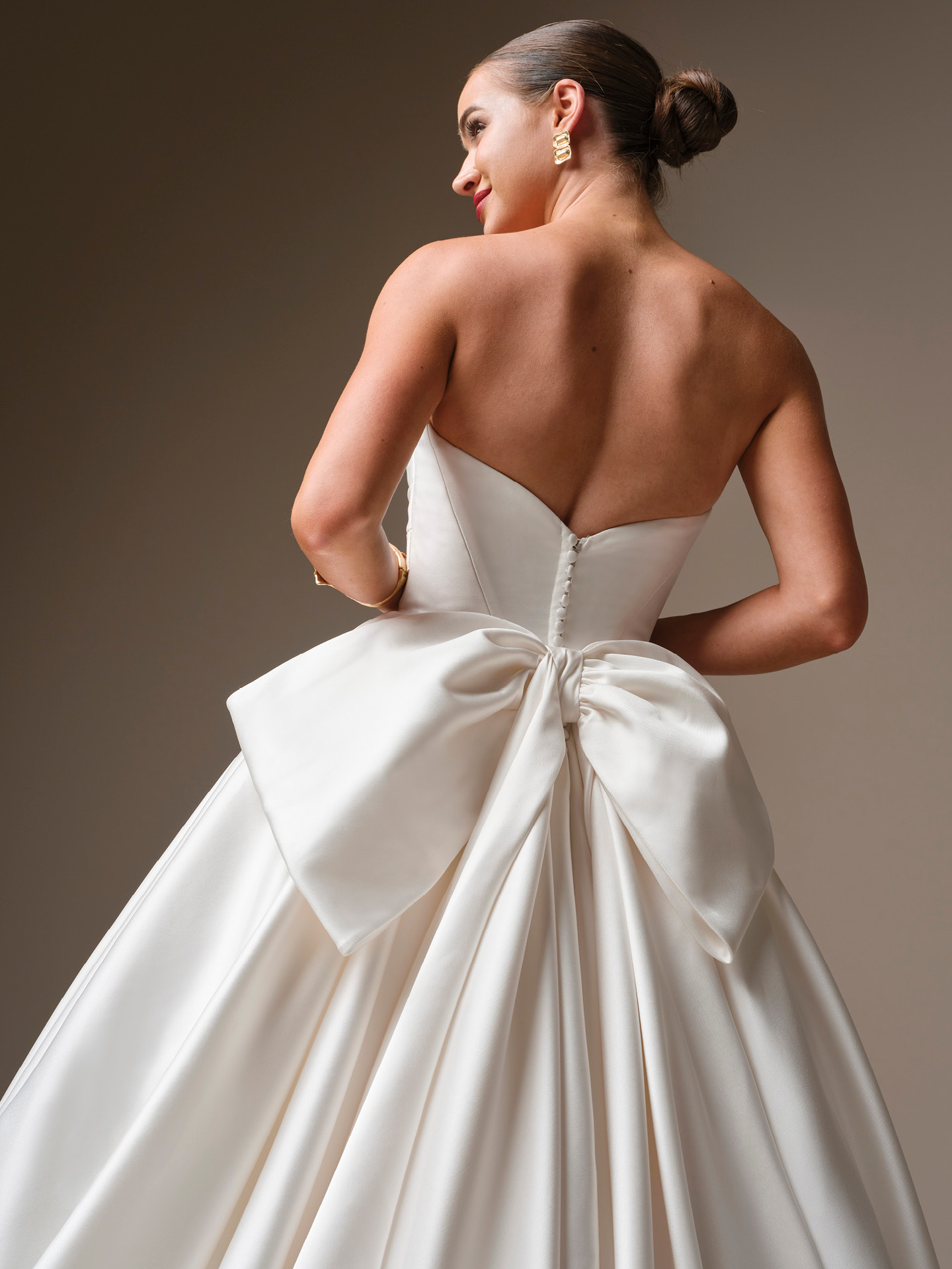 Oversized satin bridal bow attached at the back waist, creating a dramatic, statement-making focal point on a strapless ballgown.