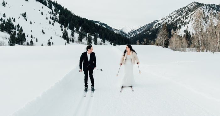 Bride wearing Drew by Maggie Sottero, one of our winter wedding dresses, while skiing with her husband