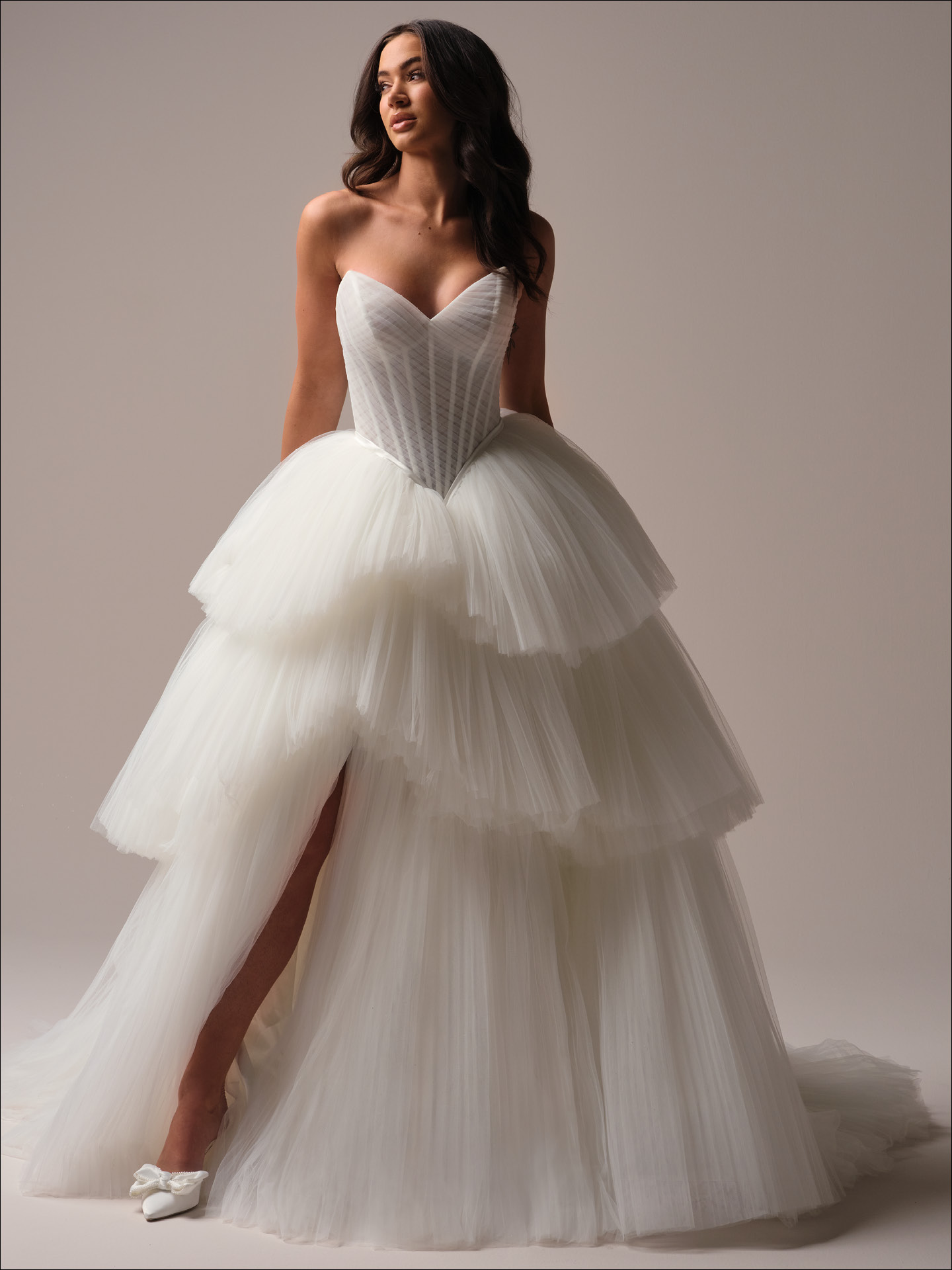 Strapless pleated tulle ballgown wedding dress with structured corset bodice, tiered skirt, and high slit
