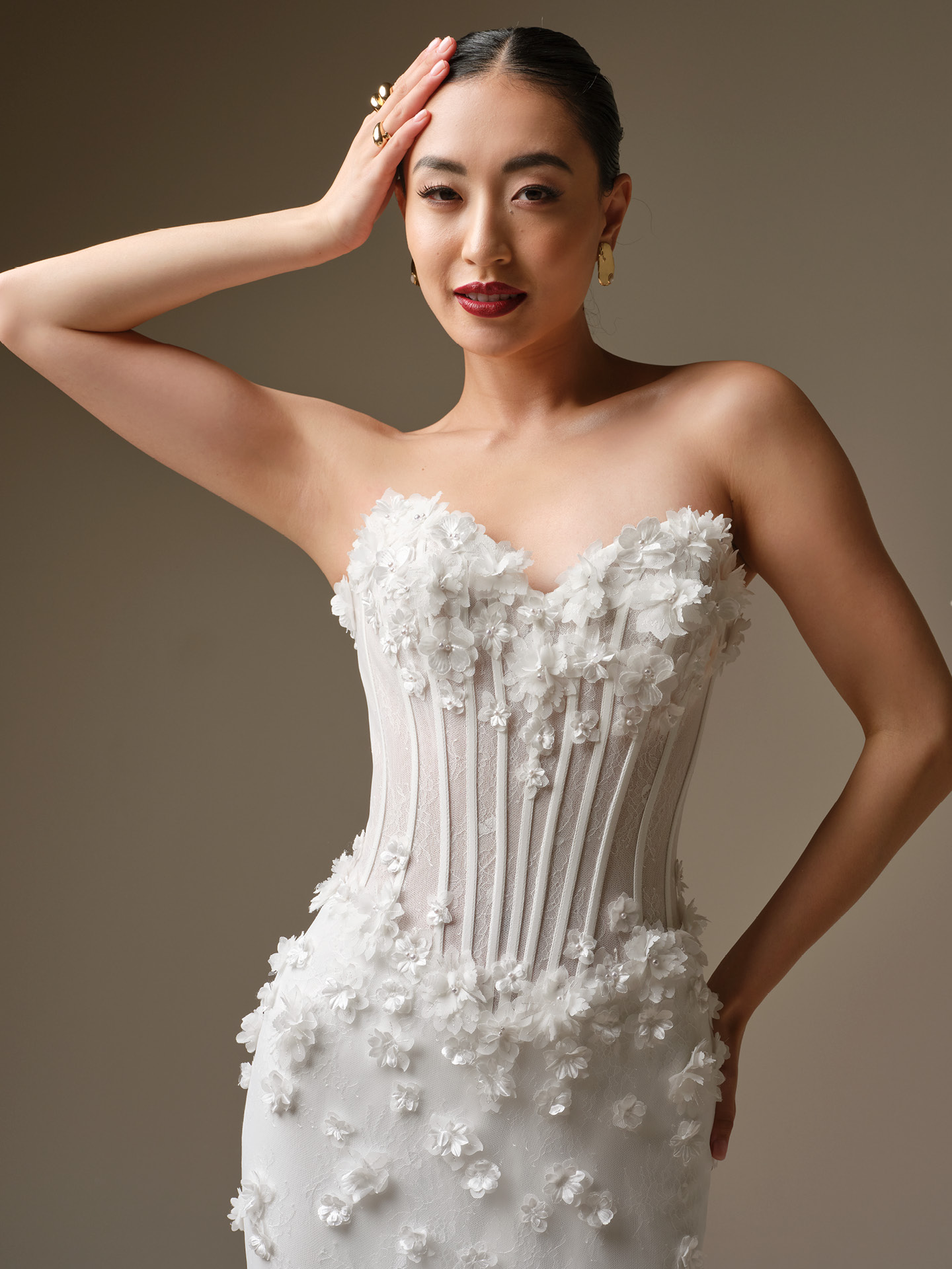 Close-up of strapless wedding dress with sheer corset bodice, exposed boning, and 3D floral details