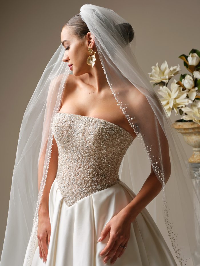 Close-up of the Dmara wedding dress by Sottero and Midgley highlighting the strapless corset-style bodice adorned with intricate pearl beading and a structured, regal fit.