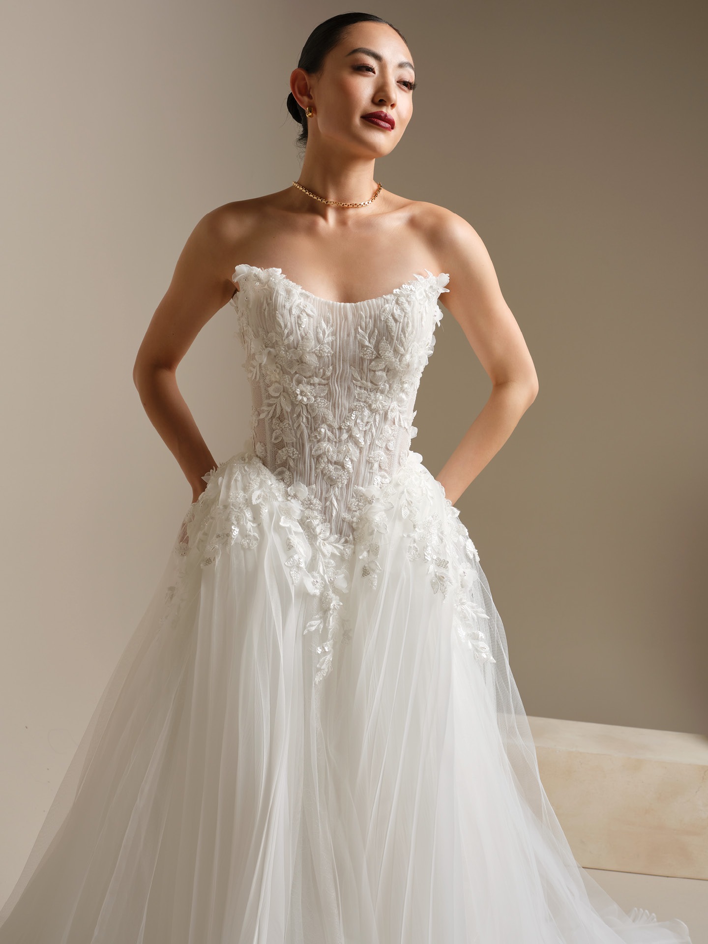 Close-up of strapless wedding dress with textured 3D floral lace bodice and layered tulle skirt