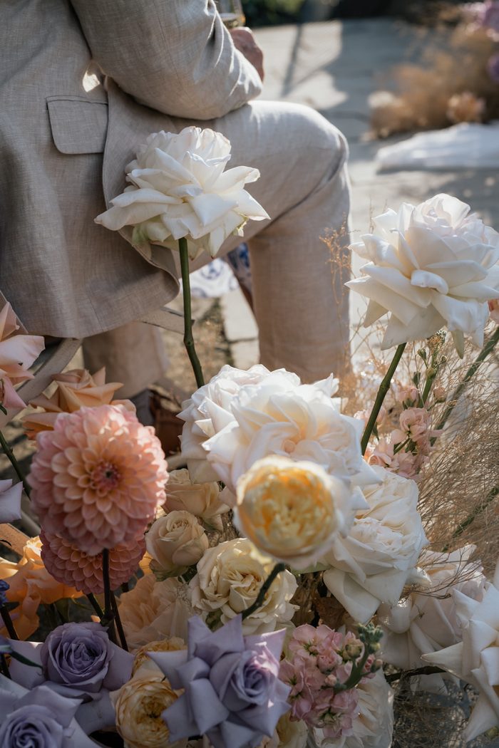 Aisle flowers next to a man sitting for the ceremony