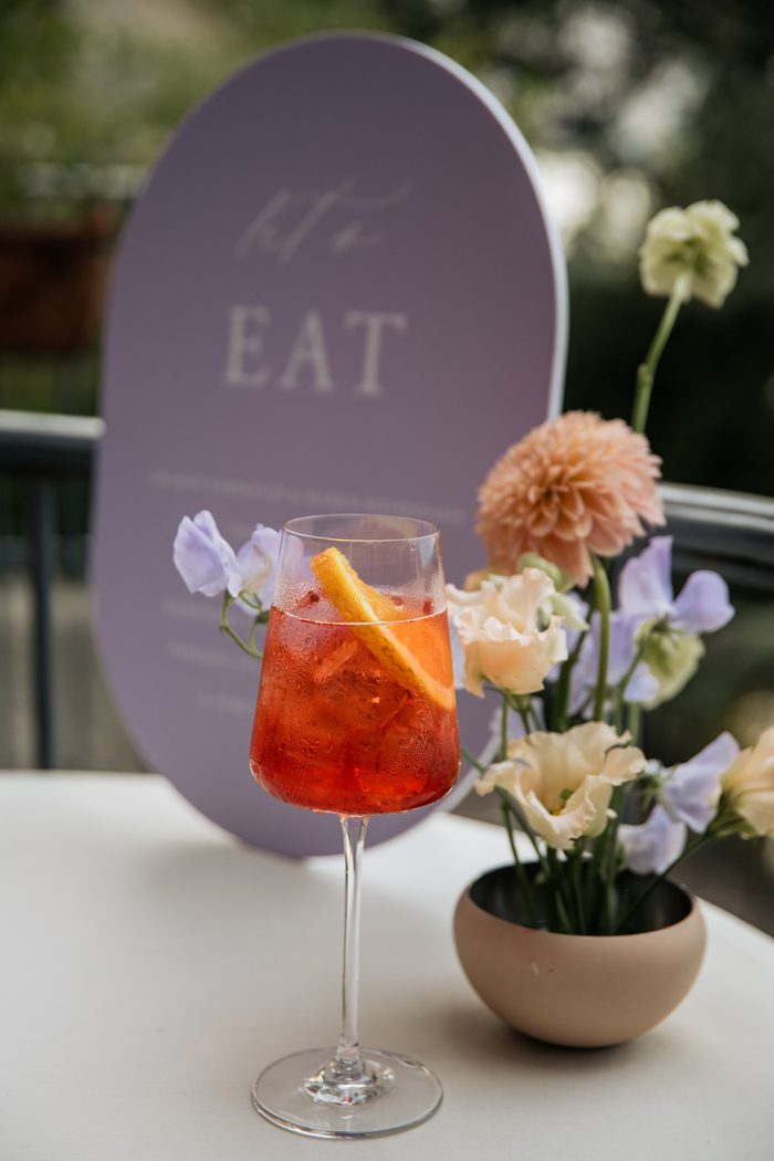 Beverage and flowers next to a drink sign