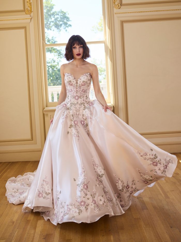 Close-up of the Alvarez ballgown wedding dress featuring a strapless sweetheart neckline, sheer corset bodice, and bold allover floral lace appliqués in soft pastel tones, styled indoors in natural window light.