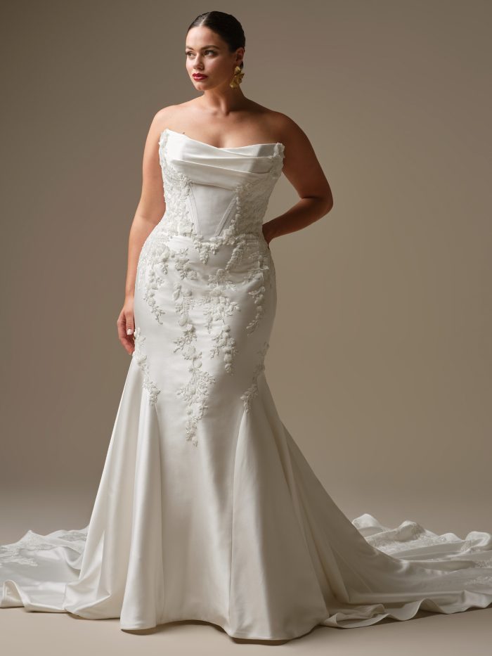 Curve model wearing Burke by Sottero and Midgley — strapless fit-and-flare satin wedding dress with draped scoop neckline, exposed corset details, and beaded lace appliqués throughout the skirt and bodice.