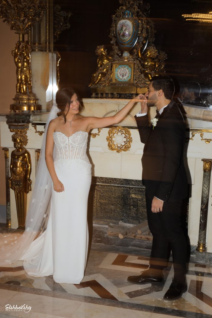 Bride holding groom's hand at wedding wearing a veil and pearl wedding gown