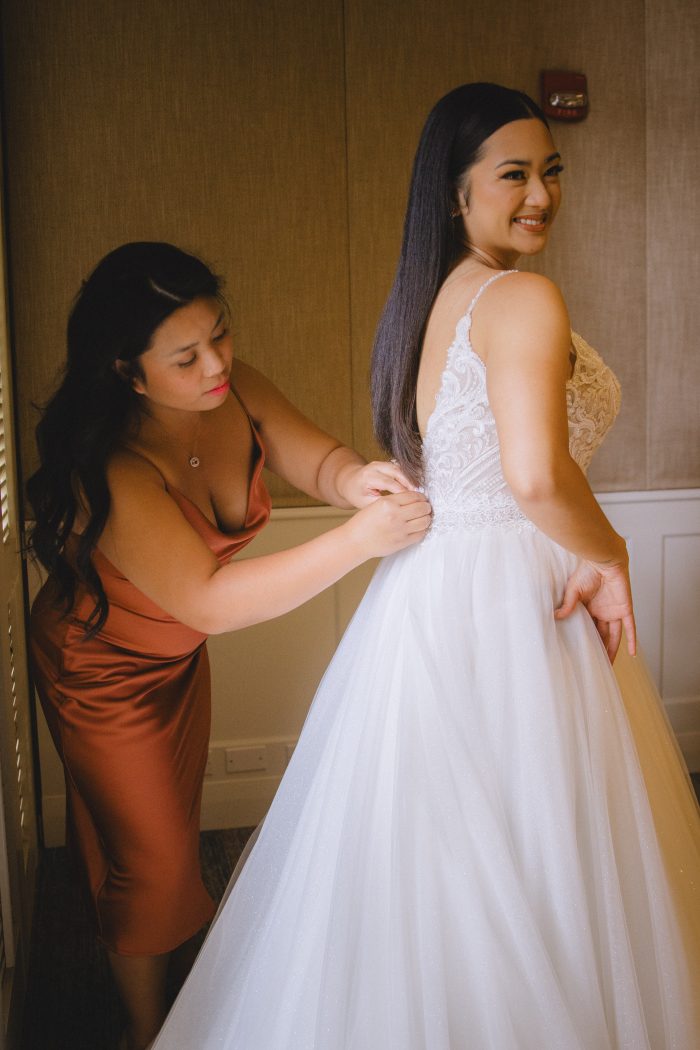 Sister zipping up an influencer's wedding dress