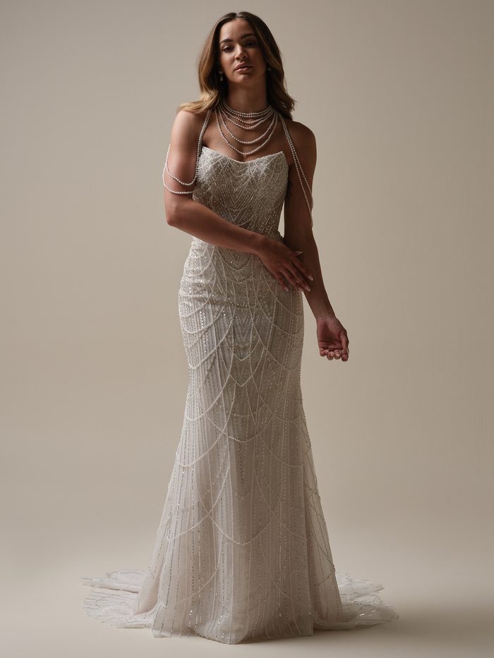 Full-length view of the Constance sheath wedding dress by Sottero and Midgley, featuring a strapless sweetheart bodice with sequin beading, draped pearl chain straps and necklace, and a fitted sheath skirt with scalloped pearl-draped detailing and a train.