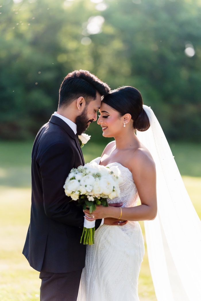 Groom holding bride wearing a sexy fit and flare wedding dress with beading