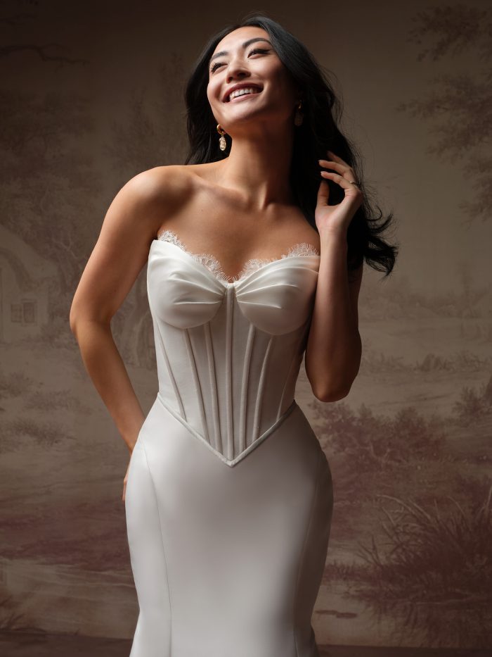Rebecca Ingram Zorina Lane fit-and-flare wedding dress featuring a strapless sweetheart corset bodice with delicate lace trim and structured boning, shown in a close-up studio portrait.