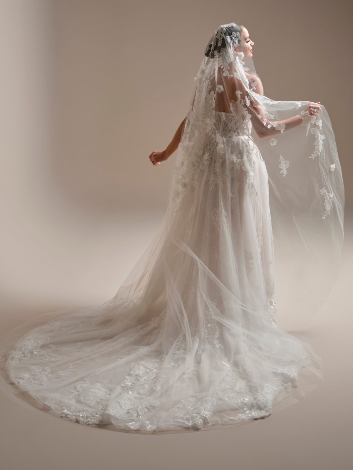 Bride wearing the Twilight Lane veil by Sottero and Midgley, featuring a cathedral-length design with intricate beaded and sequin lace motifs and dimensional floral details.