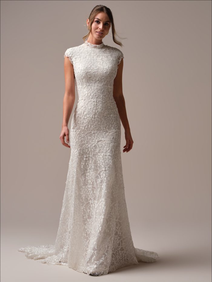 Bride wearing a timeless sheath wedding dress with cap sleeves, high illusion lace neckline, and elegant floral lace from bodice to hem.