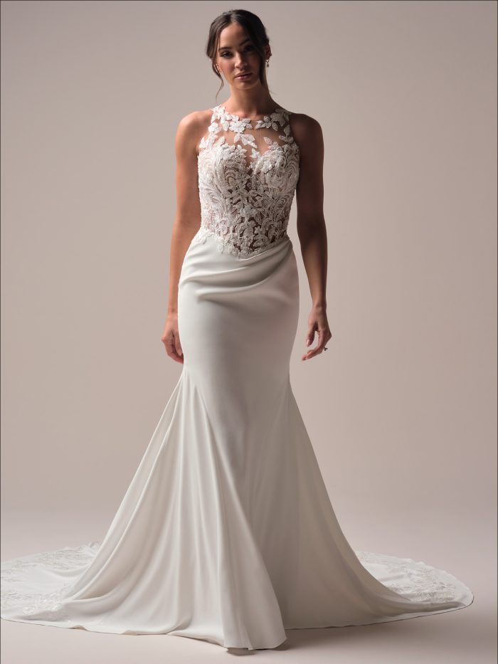 Front view of the Florentina sheath wedding dress, featuring a high illusion halter neckline, intricately beaded lace bodice, and a sleek crepe skirt with a soft train, styled in a studio setting.