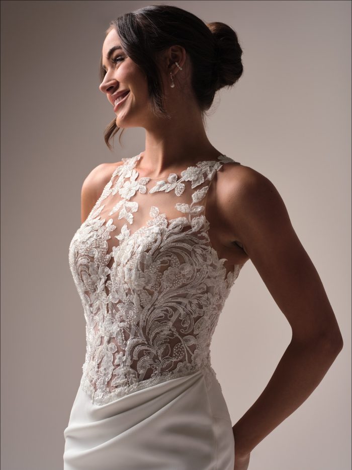 Close-up side view of the Florentina wedding gown, highlighting the illusion halter neckline, floral lace appliqués, and sheer lace bodice, worn by a smiling bride with a soft updo.