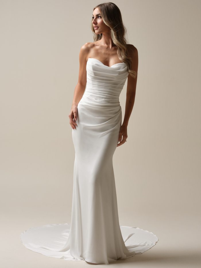 Bride in a strapless ruched satin sheath wedding dress with a sweetheart neckline and soft chapel-length train.