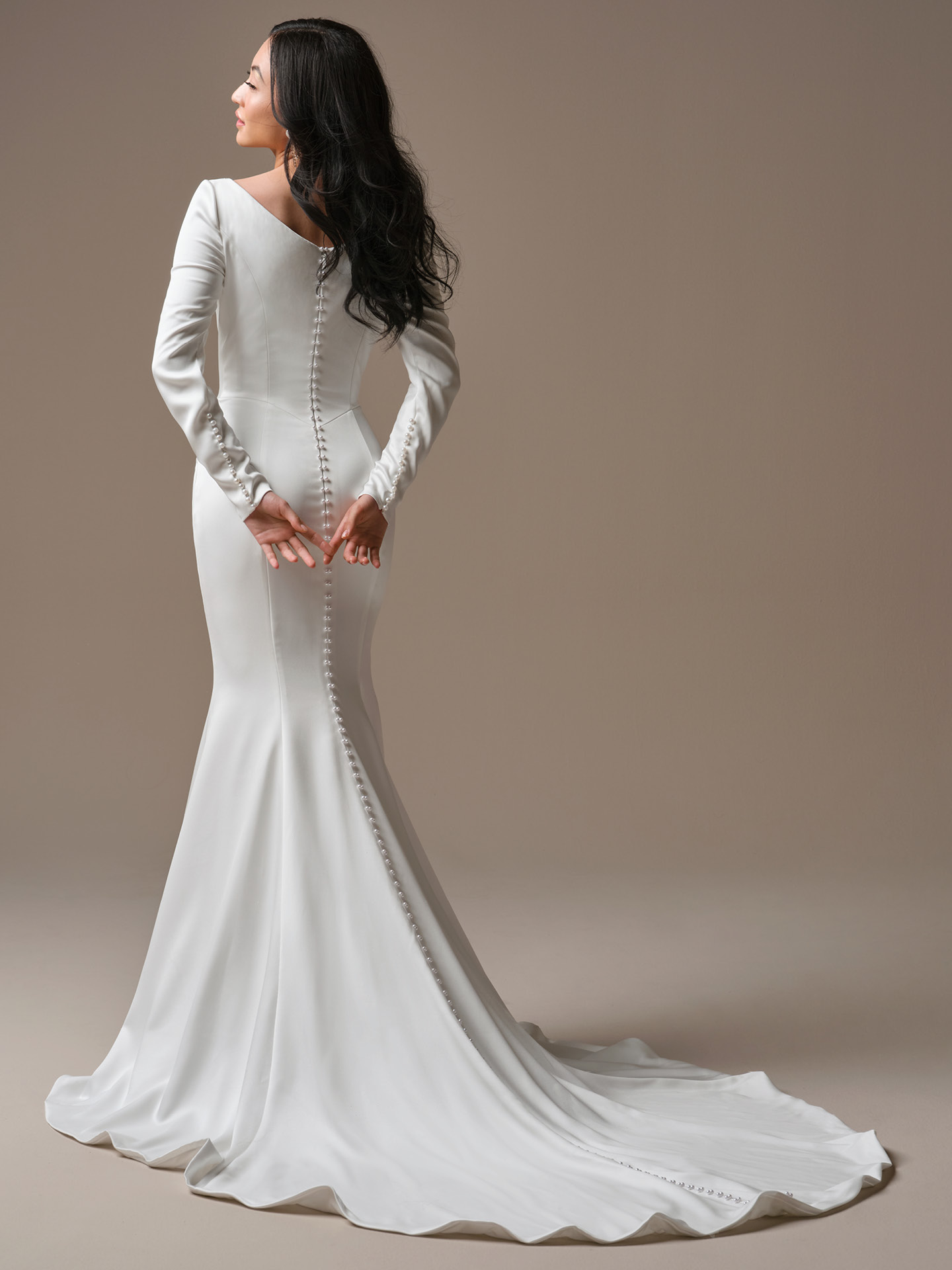 Maggie Sottero Melinda wedding dress back view with soft V-back and pearl button detail trailing down the train, showcasing a refined, minimalist silhouette