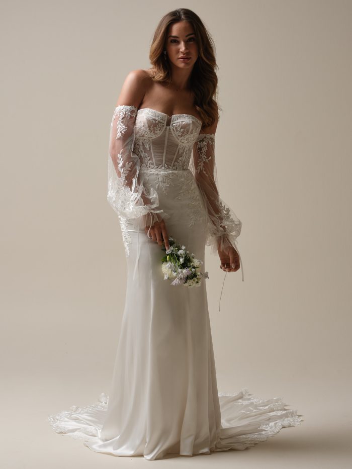 Bride in Persephone, a sleek fit-and-flare wedding gown with sheer lace bodice and detachable puff sleeves—Gen Z bridal meets modern sophistication.