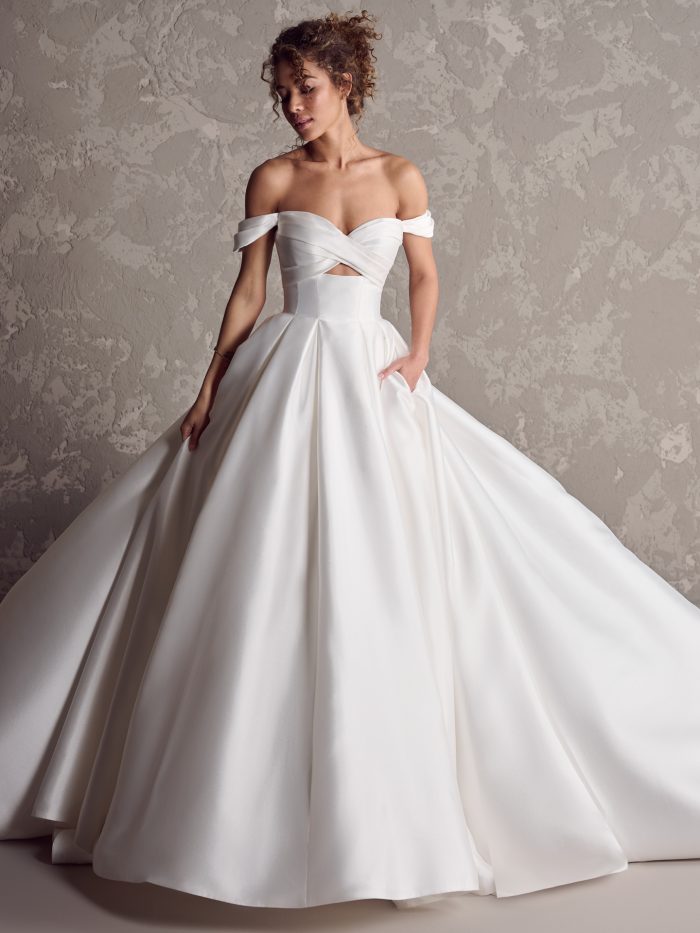 Maggie Sottero Zinaida ballgown wedding dress with off-the-shoulder straps, pleated bodice, and dramatic satin skirt.