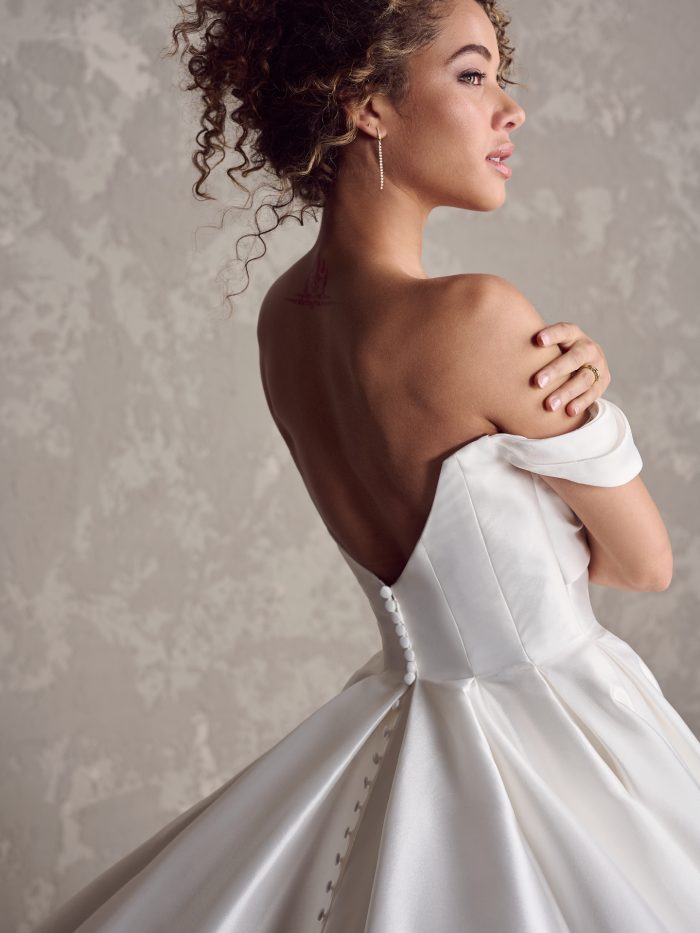Close-up of the Zinaida gown's back, featuring a low V-back, button detailing, and full pleated satin skirt—perfect for wedding gowns for petite brides wanting timeless drama.