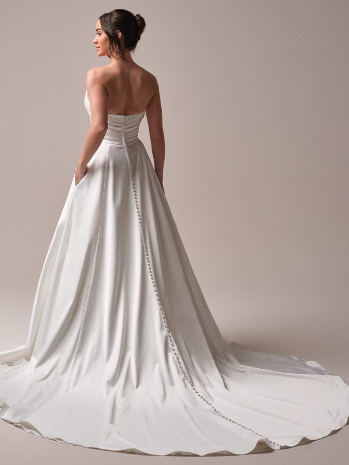 Back view of the Hannah wedding dress featuring satin-covered buttons trailing from the bodice to the train, with hidden pockets and a soft A-line silhouette for effortless elegance.