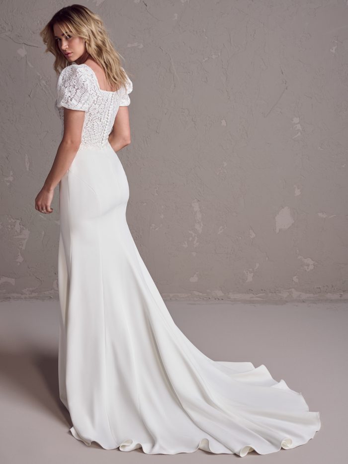 Back view of a crepe fit-and-flare gown featuring puff sleeves, a square lace back, and a soft chapel-length train for an elegant, vintage-inspired look.