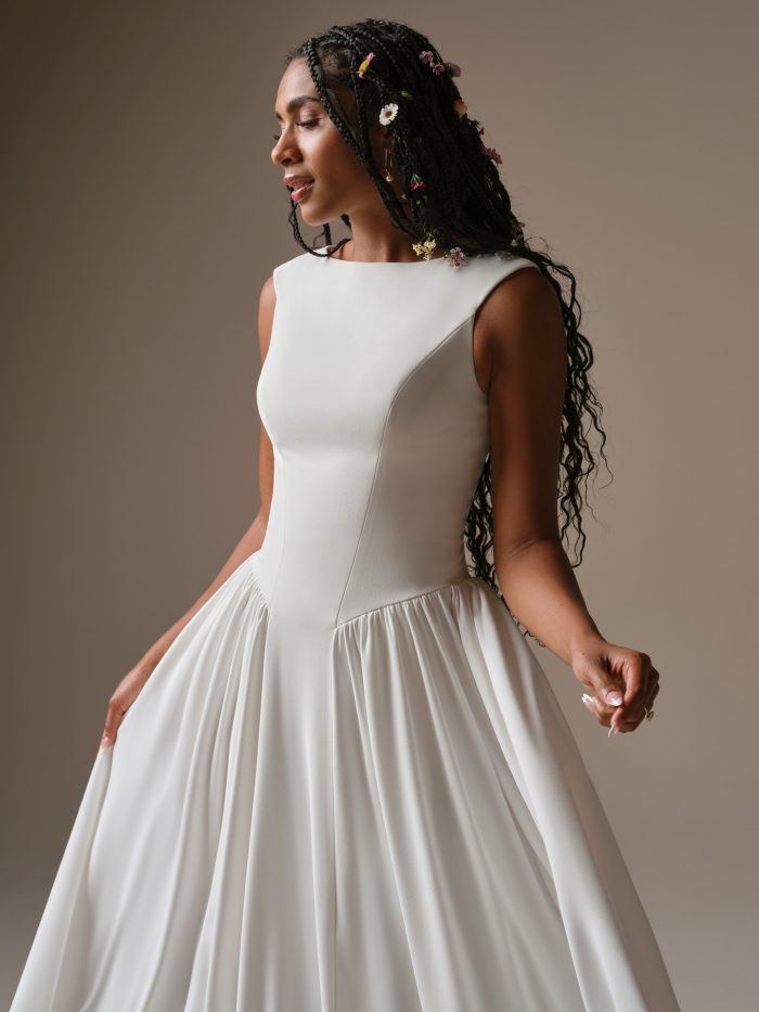 Shay by Rebecca Ingram crepe A-line wedding dress with bateau neckline, cap sleeves, and soft gathered skirt detail.