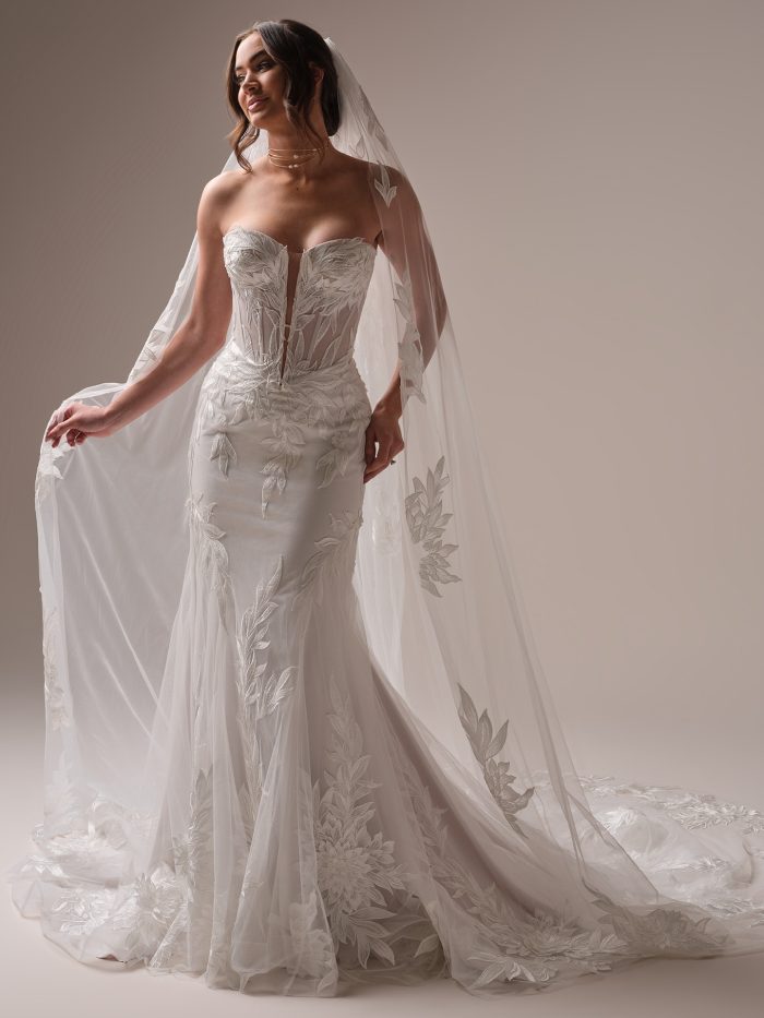 Sottero and Midgley Belladonna wedding dress featuring a strapless plunging neckline, sheer corset bodice, and bold leafy lace appliqués. This fit-and-flare bridal gown offers a modern, botanical-inspired look with striking detail and dramatic flair.