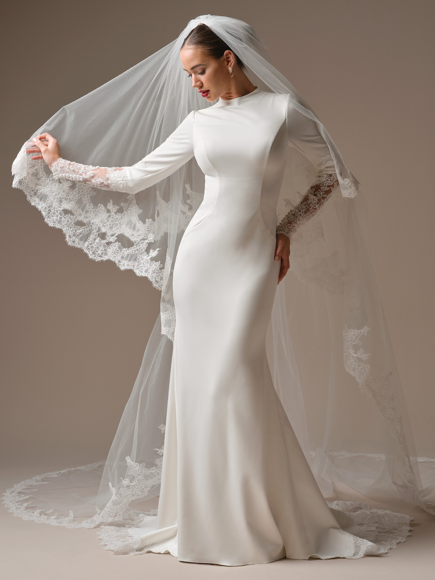 Sottero and Midgley Lovai sheath wedding dress with high neck and long sleeves, styled with a lace-trimmed cathedral veil, showcasing sleek minimalist silhouette and fitted shape