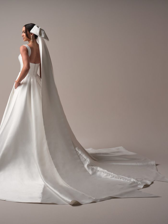 Sottero and Midgley Miko veil featuring a sleek satin finish and oversized bow detail cascading into a cathedral-length train. This modern bridal accessory adds sculptural elegance and fashion-forward drama to any minimalist wedding gown.