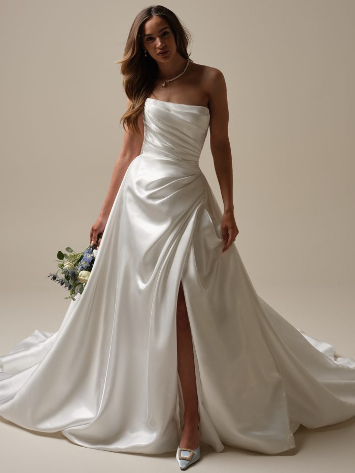 Bride wearing a strapless satin A-line wedding dress with asymmetrical ruching, a thigh-high slit, and a structured sweetheart neckline—elegant and modern.