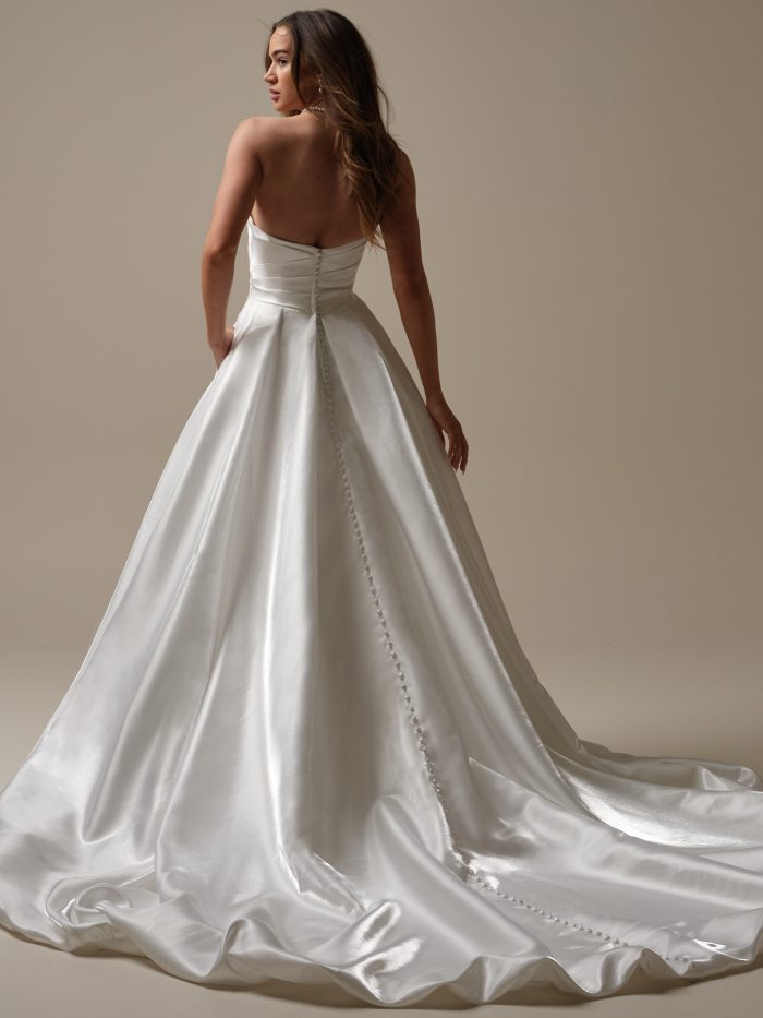 Back view of a strapless satin A-line wedding dress featuring a ruched bodice, covered button detailing down the train, and a soft, flowing skirt.