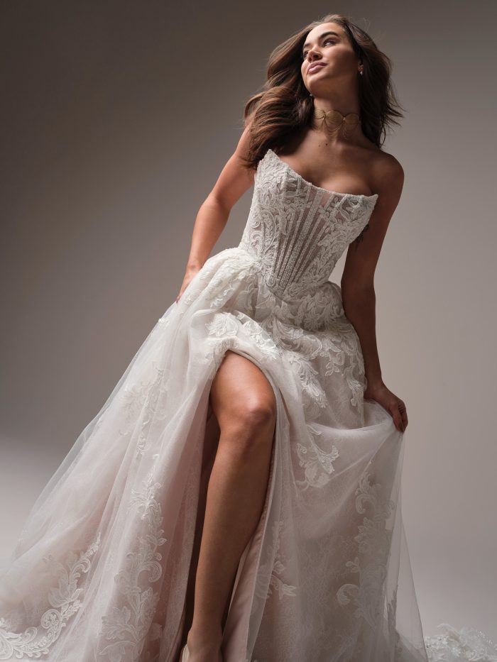 Bride wearing Parker, an embroidered A-line wedding gown with a corset-style bodice and thigh-high slit—perfect for Gen Z bridal glam with major main character energy.