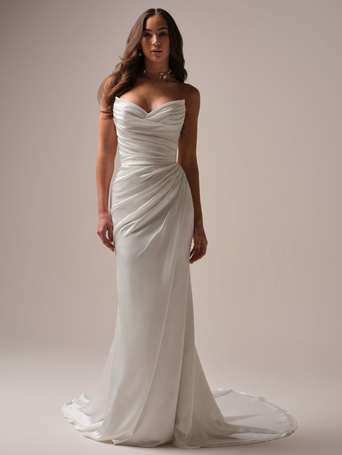 Bride wearing a strapless satin sheath wedding dress with a softly ruched bodice, sweetheart neckline, and elegant draped silhouette.